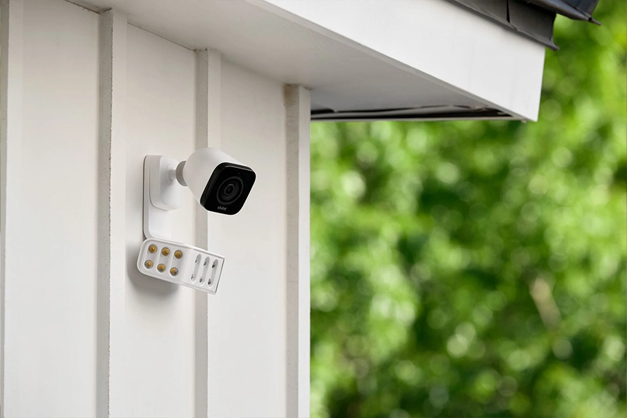 Vivint's Spotlight Pro camera perched on the side of a house with white siding